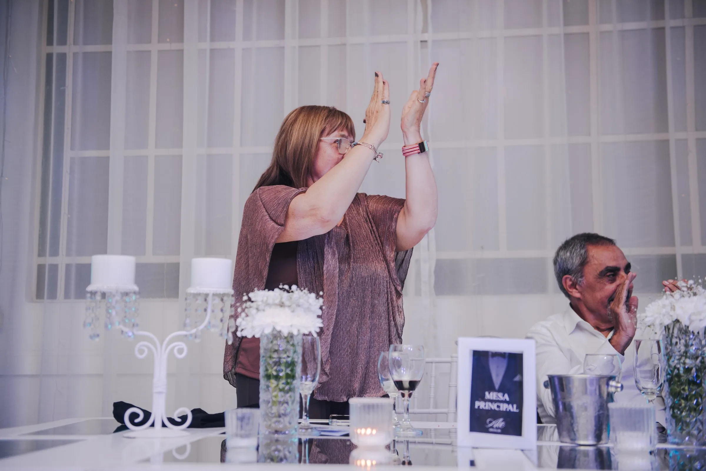 Una invitada levanta los brazos en su mesa