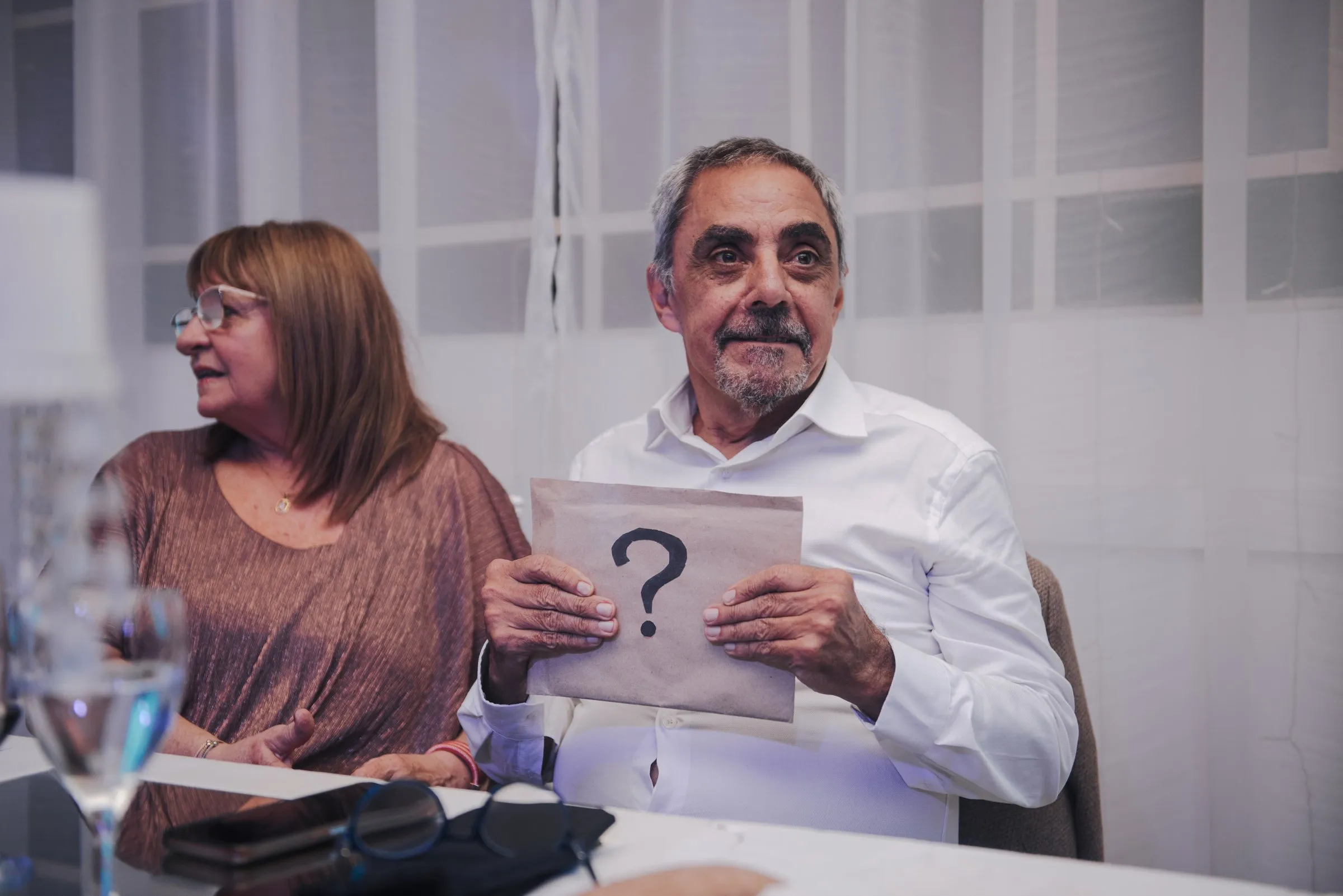 Una pareja sostiene un cartel con un signo de pregunta